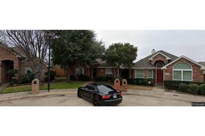 A residential street with houses, a driveway, and a parked car.