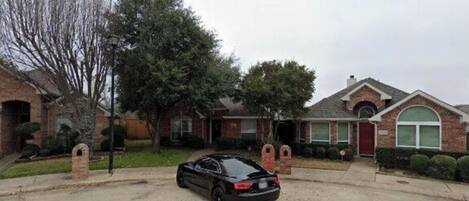 A residential driveway with a black car parked in the center.