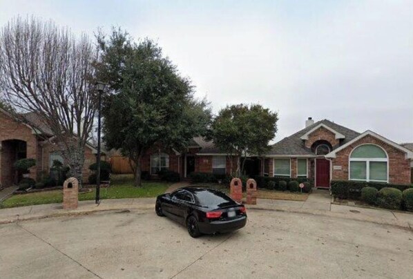 A residential driveway with a black car parked in the center.