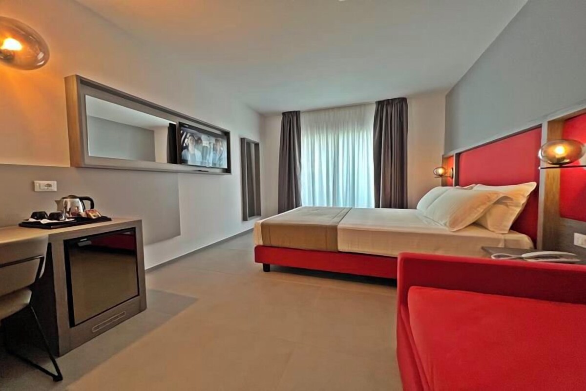 A modern hotel room with a bed, a desk, and a TV.