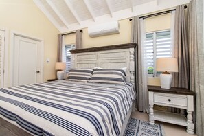 A bedroom with a large bed, a bedside table, a lamp, and a window with curtains. - Paradise Villa|Gated|Pool|Richmond (Ocho Rios)