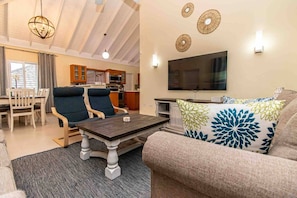 A living room with a sofa, two armchairs, a coffee table, and a TV. There is a kitchen in the background with cabinets and a microwave. - Paradise Villa|Gated|Pool|Richmond (Ocho Rios)