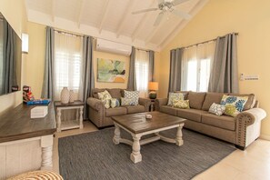 A living room with a sofa set, a coffee table, a TV, and a painting on the wall. - Paradise Villa|Gated|Pool|Richmond (Ocho Rios)