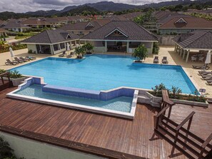 A resort with a large swimming pool, lounge chairs, and a wooden deck. - Paradise Villa|Gated|Pool|Richmond (Ocho Rios)