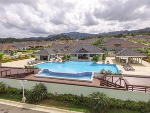 A residential area with a swimming pool, houses, and a hilly landscape in the background. - Paradise Villa|Gated|Pool|Richmond (Ocho Rios)