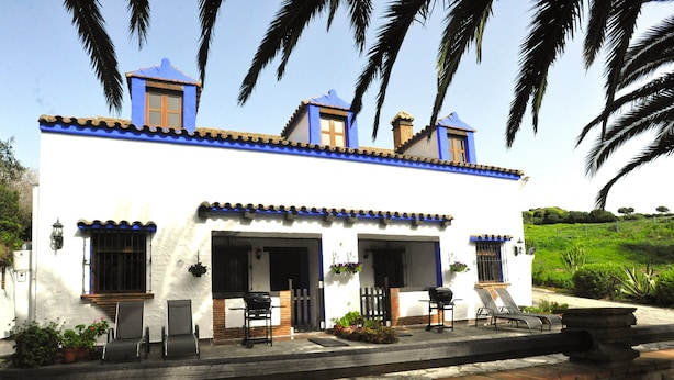 A white building with blue trim and a patio area with outdoor furniture. - Finca La Cantarera Tarifa -Poniente apartment - Reconnect with yourself + nature (Tarifa)