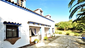 A white building with blue trim and a stone-paved courtyard. - Finca La Cantarera Tarifa -Poniente apartment - Reconnect with yourself + nature (Tarifa)