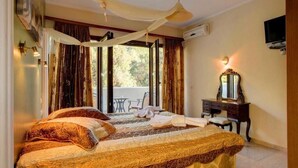 A hotel room with a large bed, a desk, a chair, a mirror, and a balcony with curtains. - Villa Thalassa Thea (Corfu)