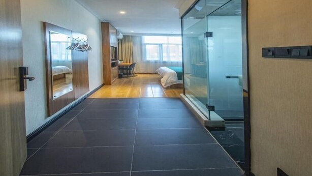 Een moderne hotelkamer met een groot bed, een bureau en een glazen scheidingswand.
