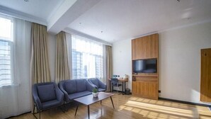 Een moderne woonkamer met een zithoek, een salontafel en een aan de muur bevestigde televisie.