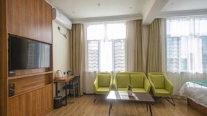 Een moderne hotelkamer met een wand van houten panelen, een flatscreen televisie, een tafeltje met stoelen en een zithoek.