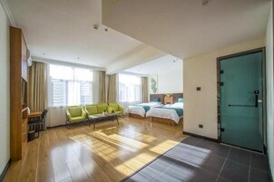 Una habitación de hotel con piso de madera, dos camas, un sofá y un escritorio.