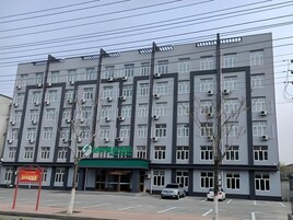 Un edificio de varios pisos con fachada plana, unidades de aire acondicionado y un toldo verde.