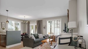 A modern living room with a grey sofa, wooden coffee table, and a dining area with a white table and chairs. - All Season Ski in/Out Chalets at Calabogie Peaks (Calabogie)