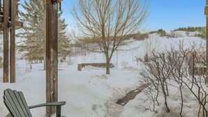 A covered outdoor area with a wooden bench and a chair, surrounded by snow-covered ground and trees. - All Season Ski in/Out Chalets at Calabogie Peaks (Calabogie)