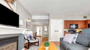 A living room with a fireplace, a sofa, a coffee table, and a TV. - All Season Ski in/Out Chalets at Calabogie Peaks (Calabogie)