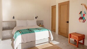 Ein Schlafzimmer mit einem Bett, einem Nachttisch, einer Holzbank und einer Wanddekoration.