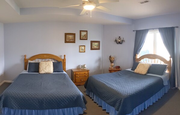 A bedroom with two beds, a ceiling fan, and a window with curtains.