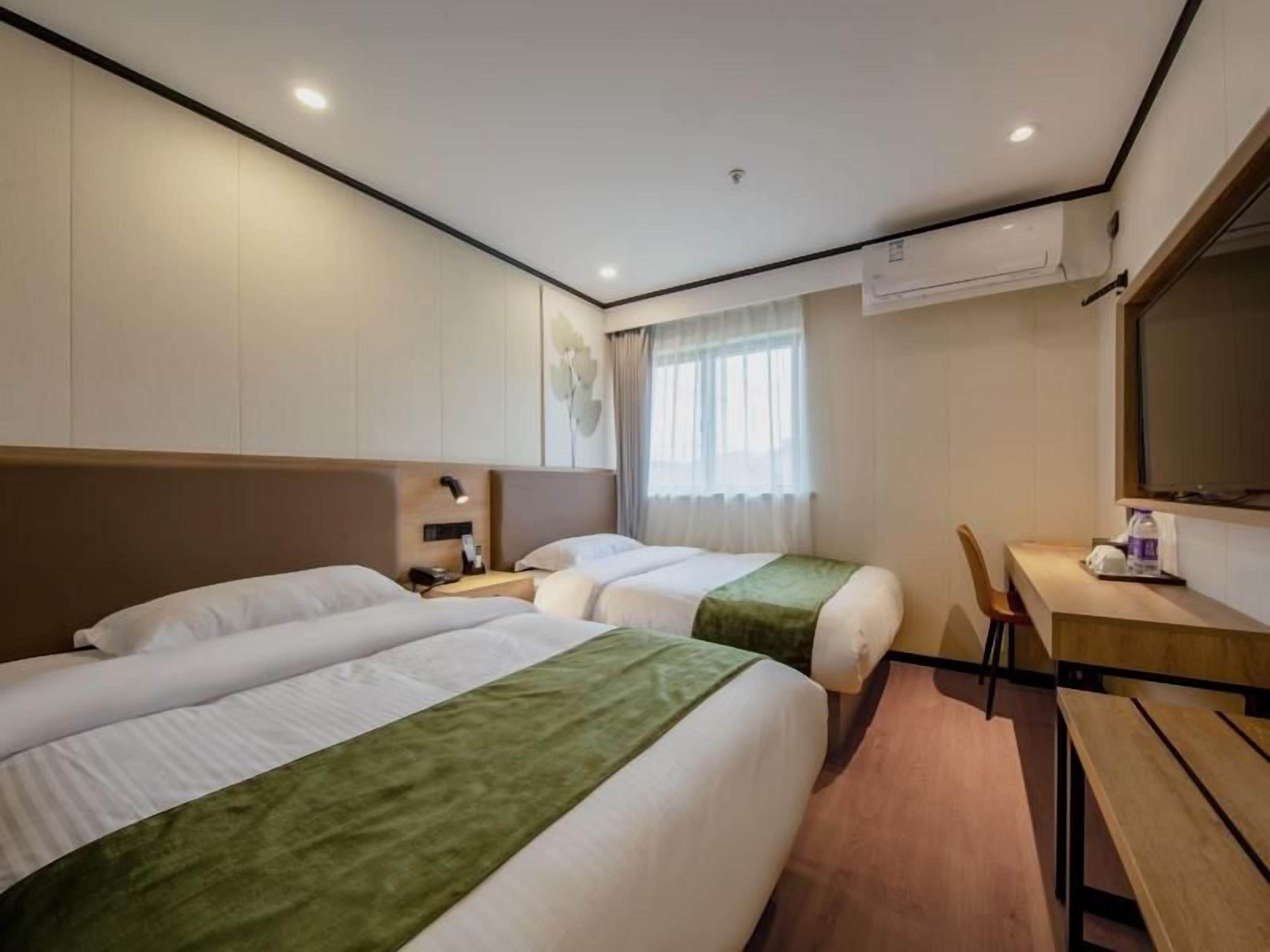 Une chambre d’hôtel avec deux lits, un bureau, une chaise et un grand miroir.