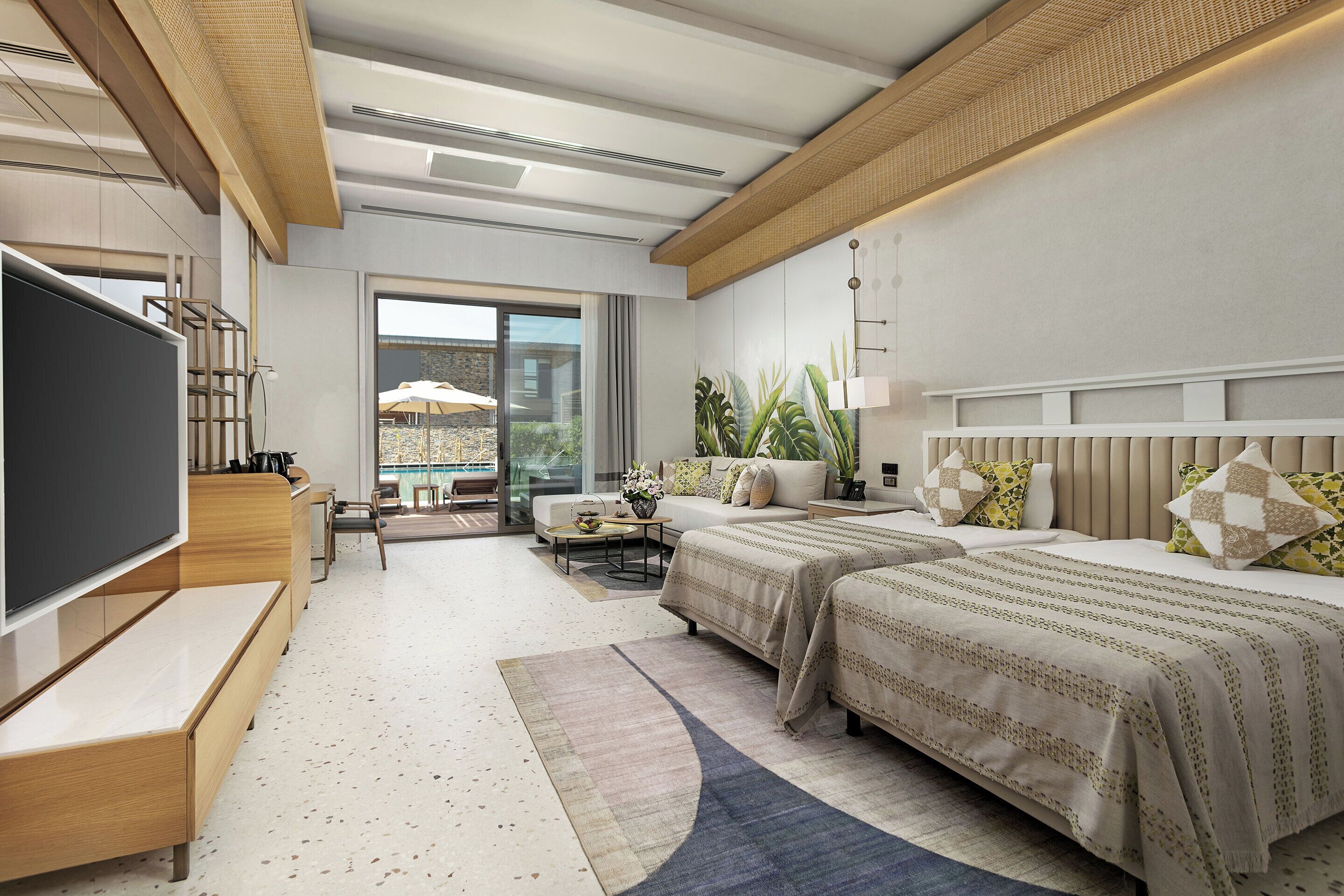 A modern hotel room with a large flat-screen TV, two beds with patterned bedding, a sofa, a coffee table, and a view of the outdoors.