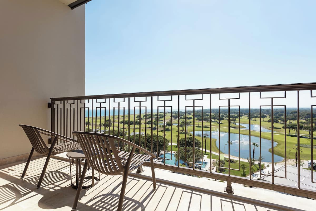 A balcony with a view of a golf course and a lake.