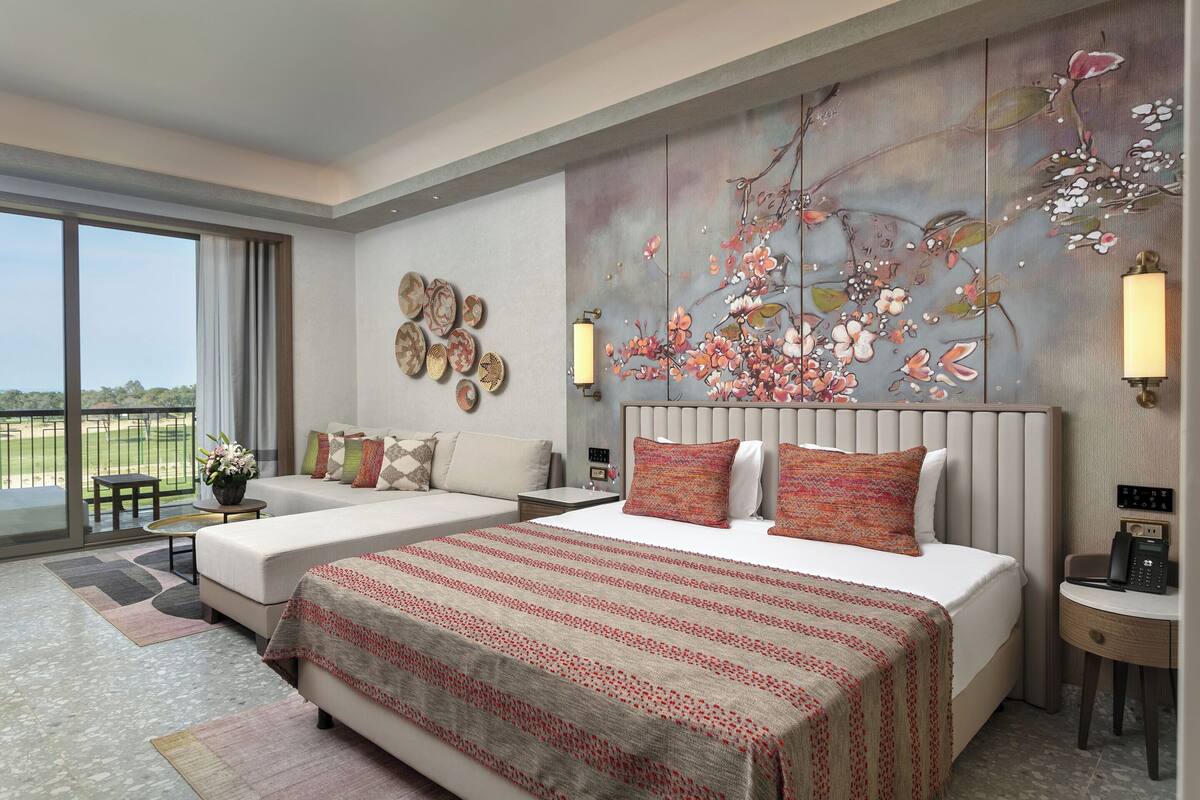A modern hotel room with two beds, a large window, and a view of the outdoors.