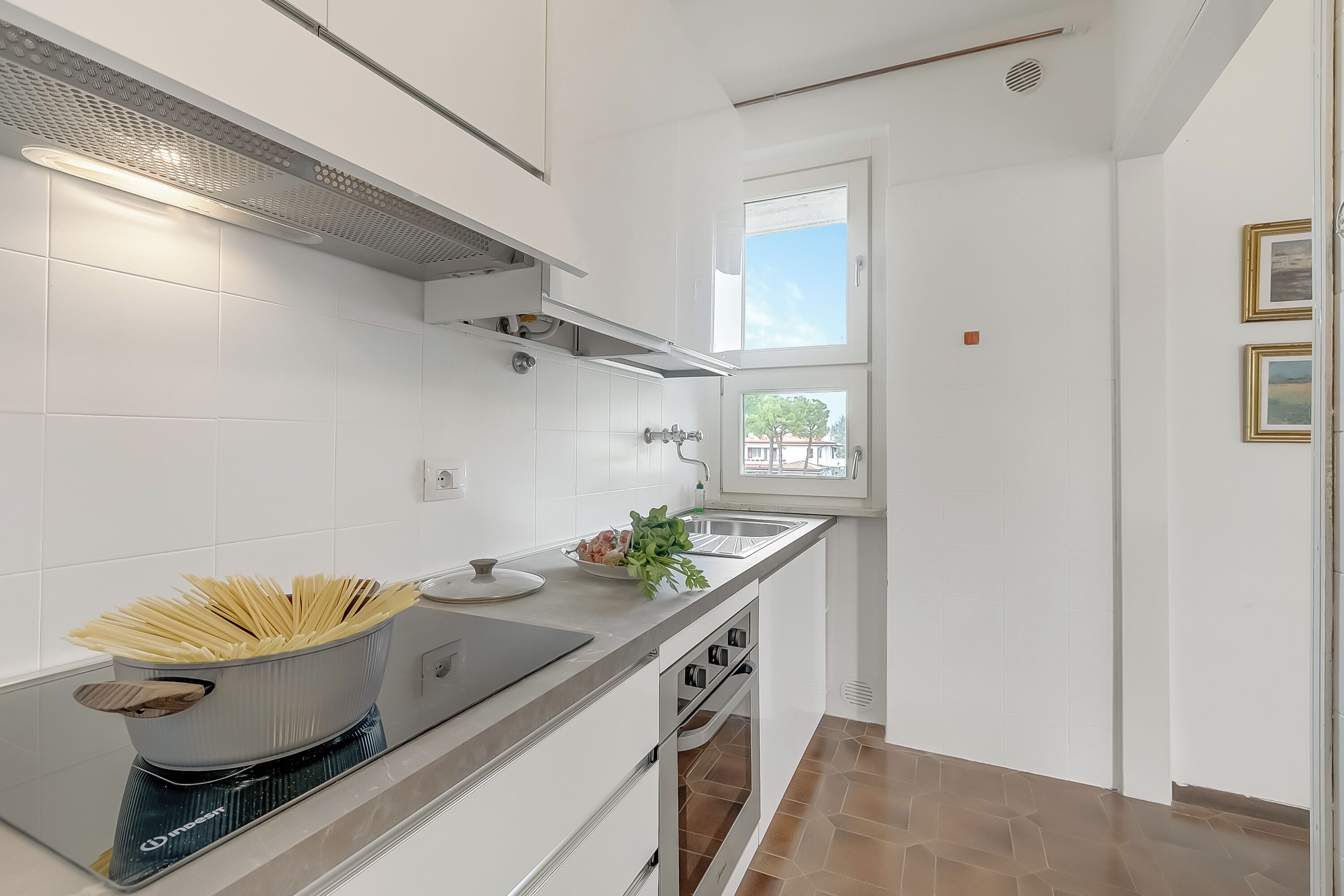 A modern kitchen with white cabinetry, a built-in oven, and a window providing natural light.