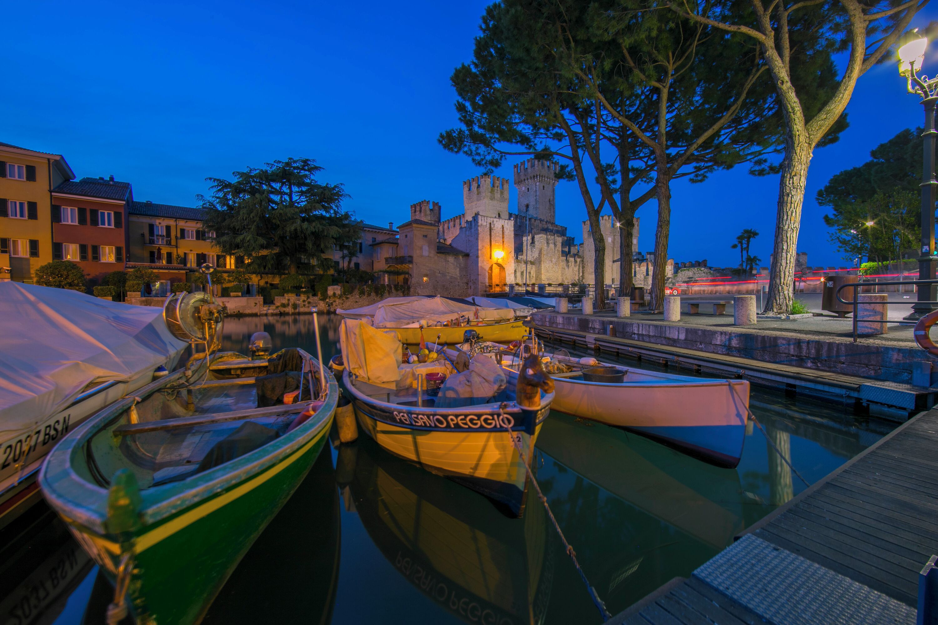 A waterfront area with boats docked, a castle, and a bridge.