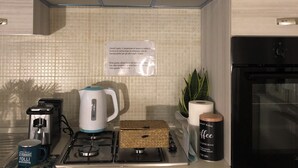 A kitchen with a stainless steel range hood, a coffee maker, a kettle, and a toaster.