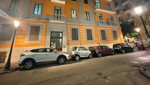 A multi-story building with a row of parked cars in front.