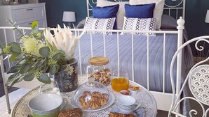 A neatly arranged breakfast setup with a variety of pastries, a glass of orange juice, and a decorative vase with flowers on a round table.