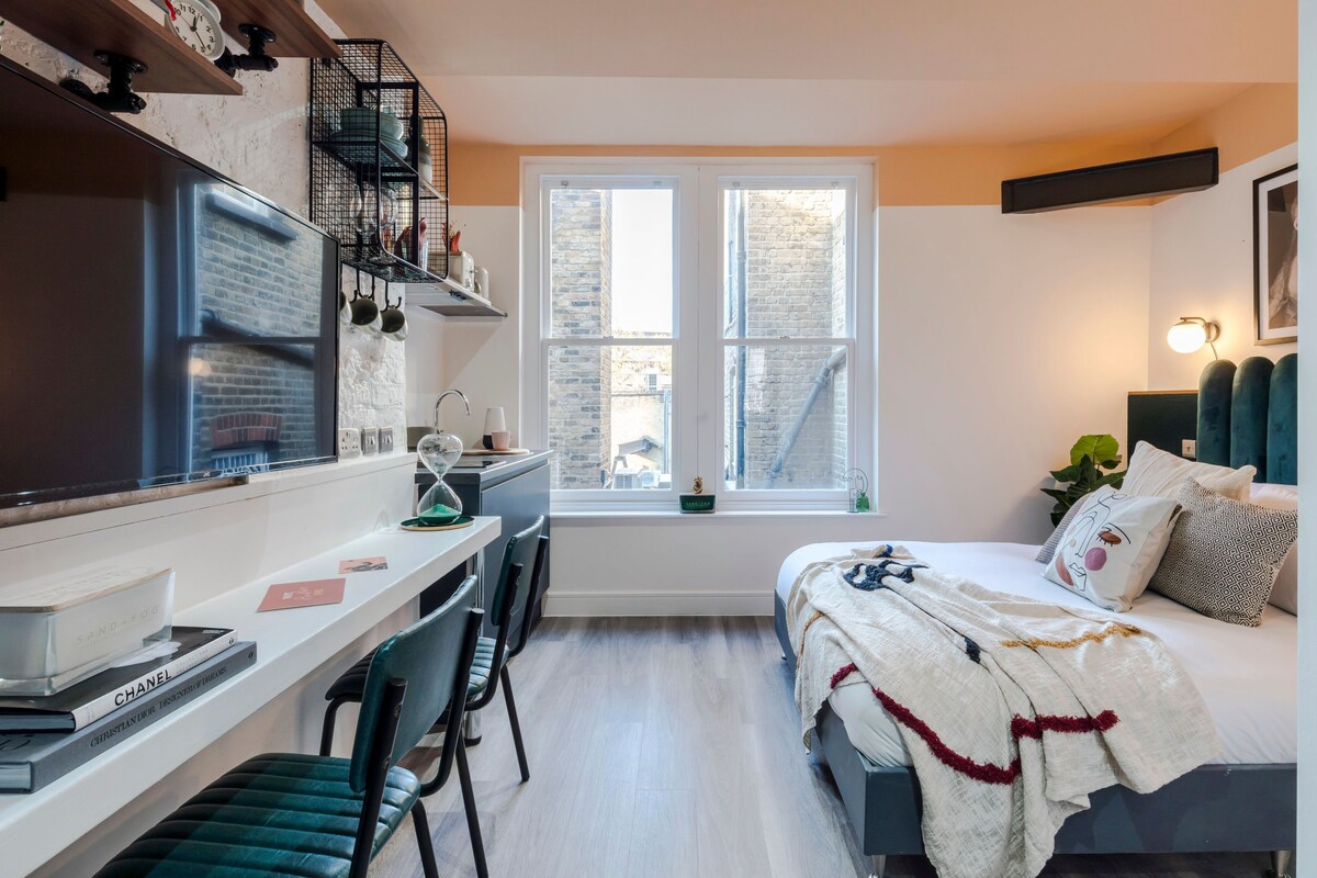 A compact bedroom with a bed, a desk, and a window.