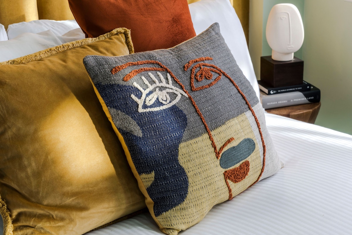 A bed with two pillows, one with a patchwork design and another solid color.