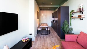 Una sala de estar moderna con un televisor de pantalla plana, un sofá rojo y un comedor con una mesa y sillas de madera.