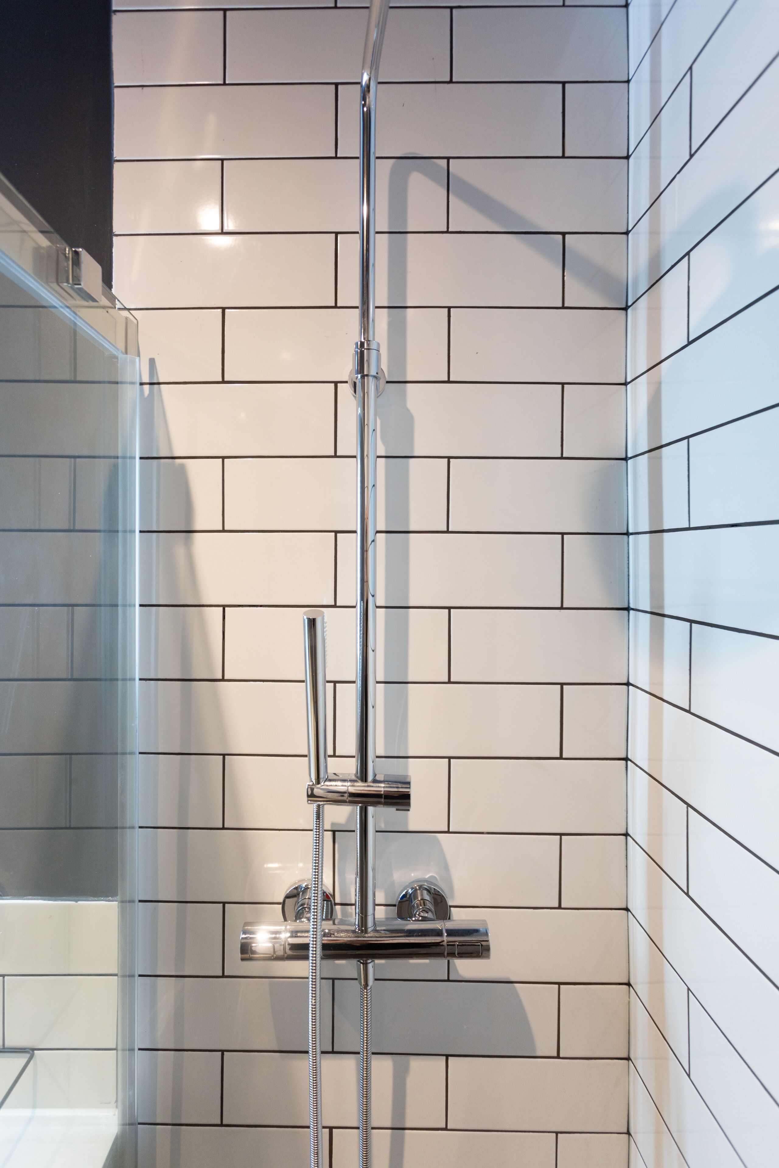 A shower with a chrome faucet and a glass enclosure.