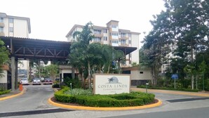 Schild für die Costa Linda Condominiums mit überdachtem Eingang, Palmen und einem mehrstöckigen Gebäude im Hintergrund.