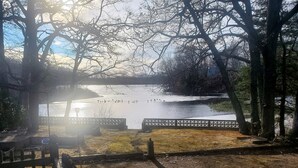 Une vue d’un lac, avec une clôture en bois et des bancs le long de la rive.