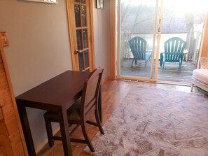 A dining area with a wooden table and chairs, a sliding glass door leading to an outdoor patio with chairs.
