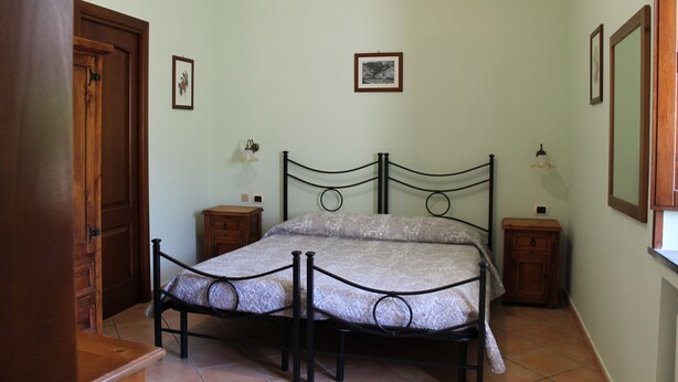 A bedroom with a bed, wooden nightstands, and a door. - Amalfi double room (Gragnano)