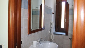 A bathroom with a white sink, a mirror, and a hairdryer on the wall. - Amalfi double room (Gragnano)