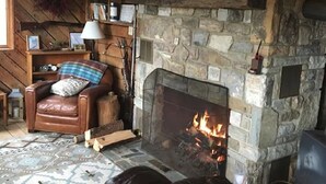 Un salón acogedor con chimenea de piedra, sofá de cuero y estantería de madera.