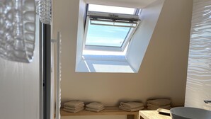 Ein modernes Badezimmer mit Oberlicht, einem Holzwaschtisch und einer Sitzbank.