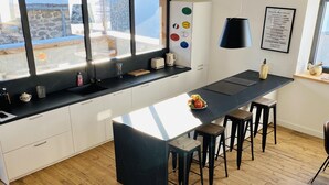 Eine moderne Küche mit großem Fenster, Holzboden und einer Essecke mit Barhocker.