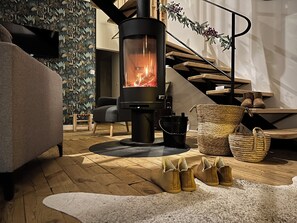 Ein gemütliches Wohnzimmer mit Kaminofen, bequemer Couch, Treppe und dekorativem Girlande.