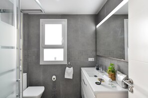 Une salle de bain moderne équipée de toilettes, d’un lavabo et d’un espace douche.