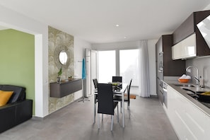 A modern kitchen with a dining area, a built-in oven, and a large window.