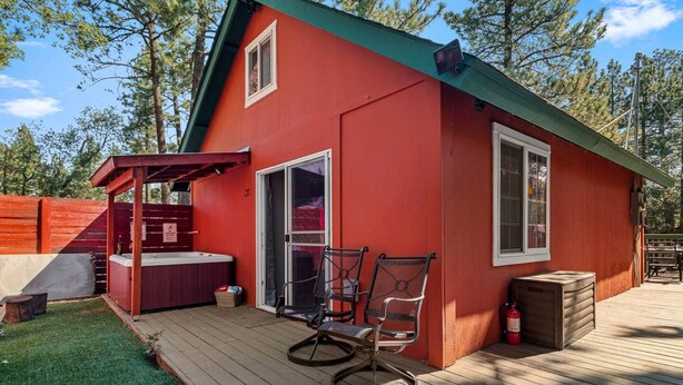 Una cabaña roja con terraza, jacuzzi y dos sillas.