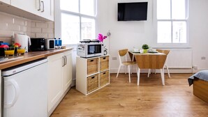 A compact kitchen with white cabinets, a microwave, and a small dining area with a table and chairs.