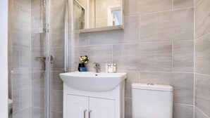 A modern bathroom with a glass shower enclosure, a white sink, and a toilet.