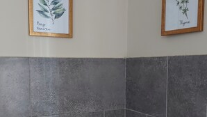 Una cocina con estufa a gas, baldosas grises e impresiones botánicas enmarcadas en la pared.